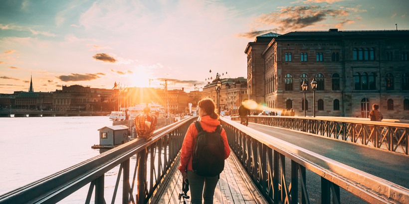Stockholm, Sweden. Young Caucasian Woman Lady Tourist Traveler Walking On Famous Skeppsholmsbron - Skeppsholm Bridge. Popular Place, Landmark And Destination In Stockholm, Sweden.